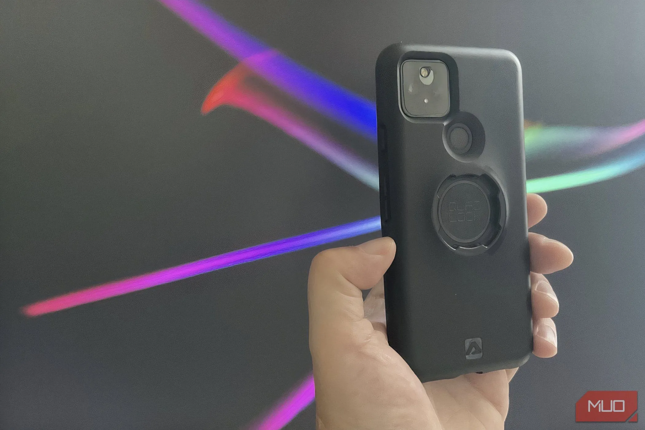 Bàn tay đang giữ một chiếc smartphone được bảo vệ bởi ốp lưng Quad Lock chắc chắn, minh họa lợi ích của việc sử dụng phụ kiện bảo vệ điện thoại.