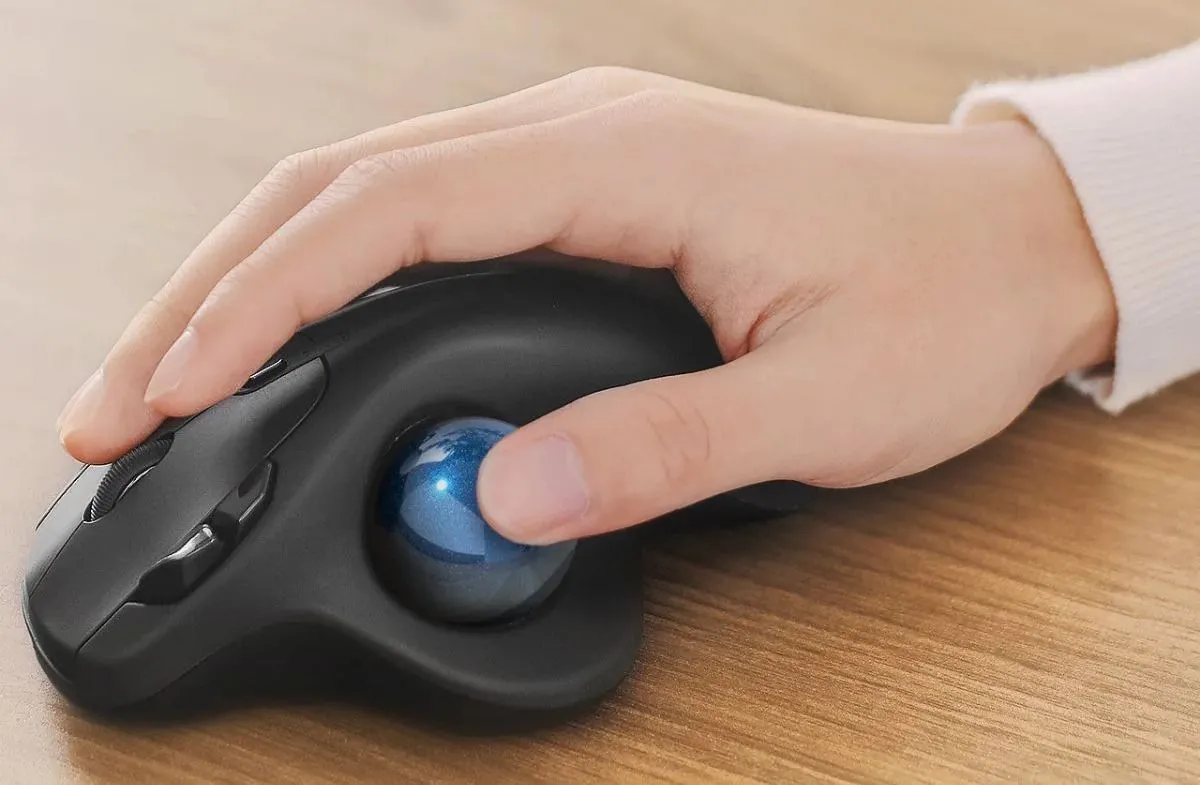 Bàn tay đang sử dụng chuột trackball điều khiển bằng ngón cái, thể hiện cách cầm nắm tự nhiên và thoải mái.