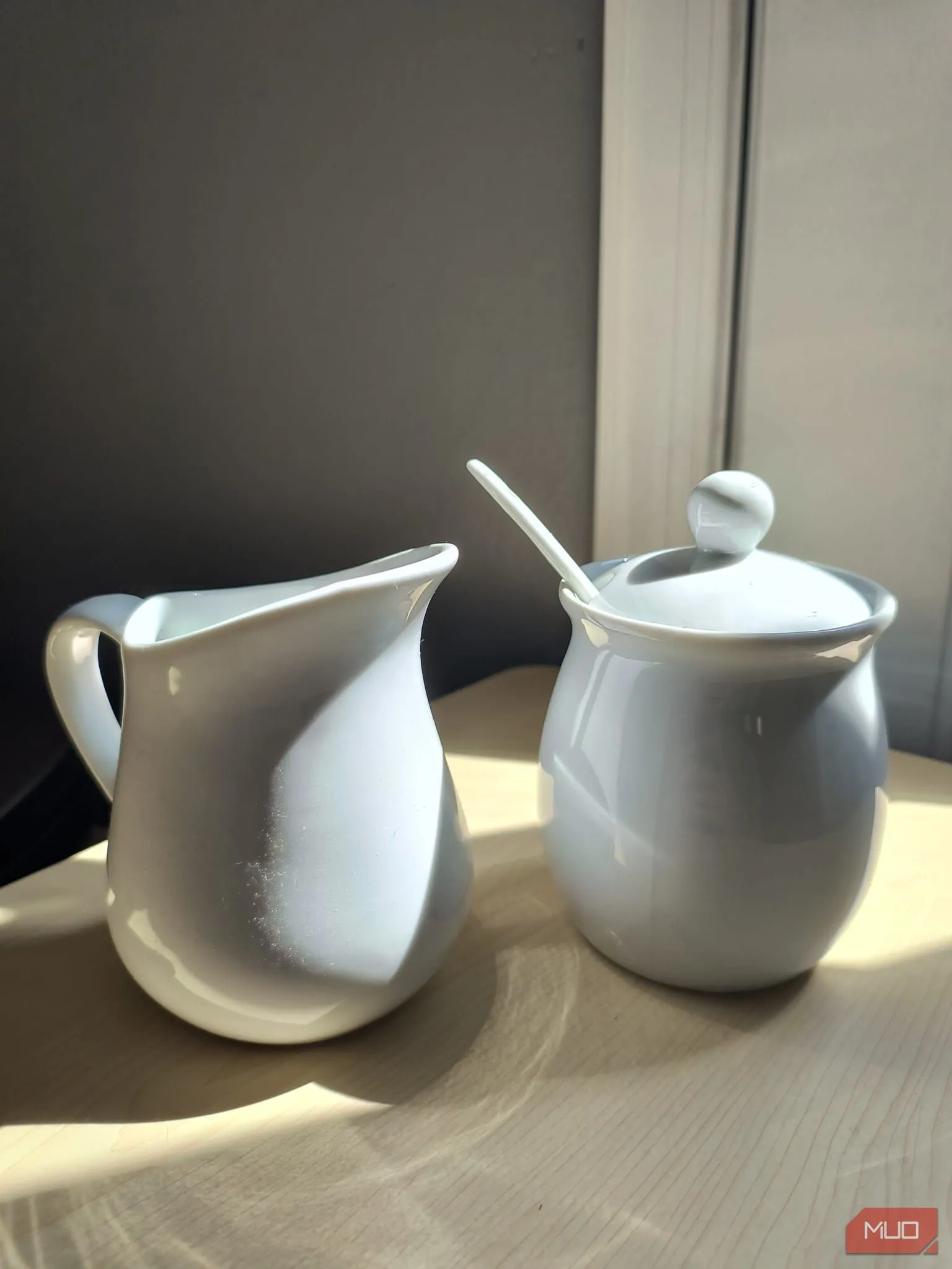 Bộ ấm chén sứ trắng đặt dưới nắng trực tiếp có HDR