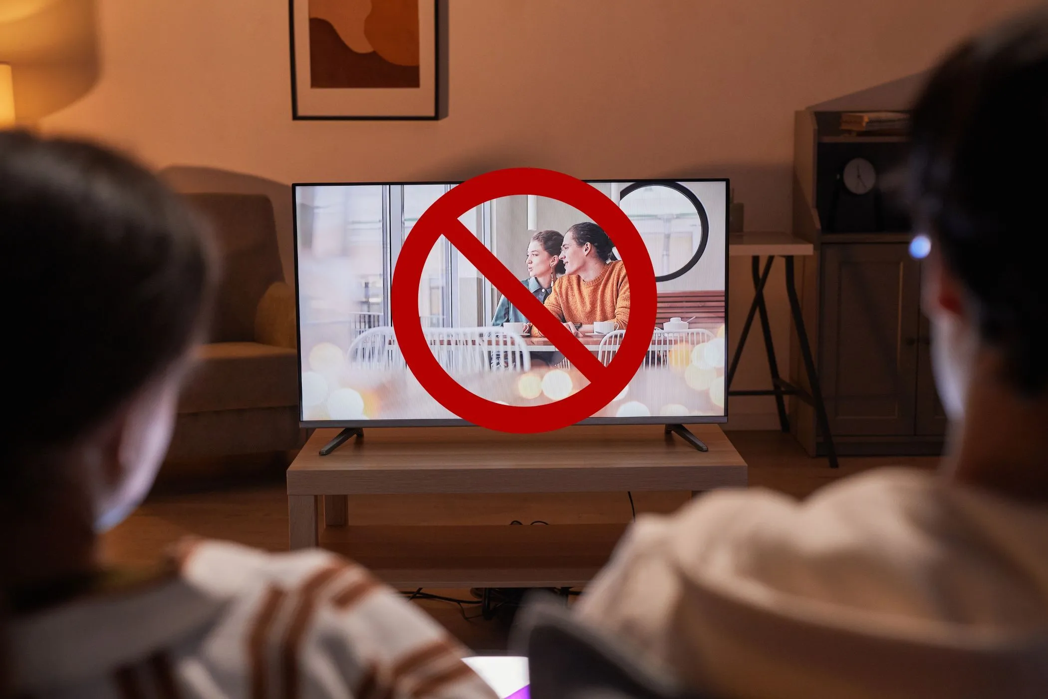 Cặp đôi xem TV với biểu tượng cấm, minh họa việc sử dụng băng thông khi kiểm tra tốc độ internet