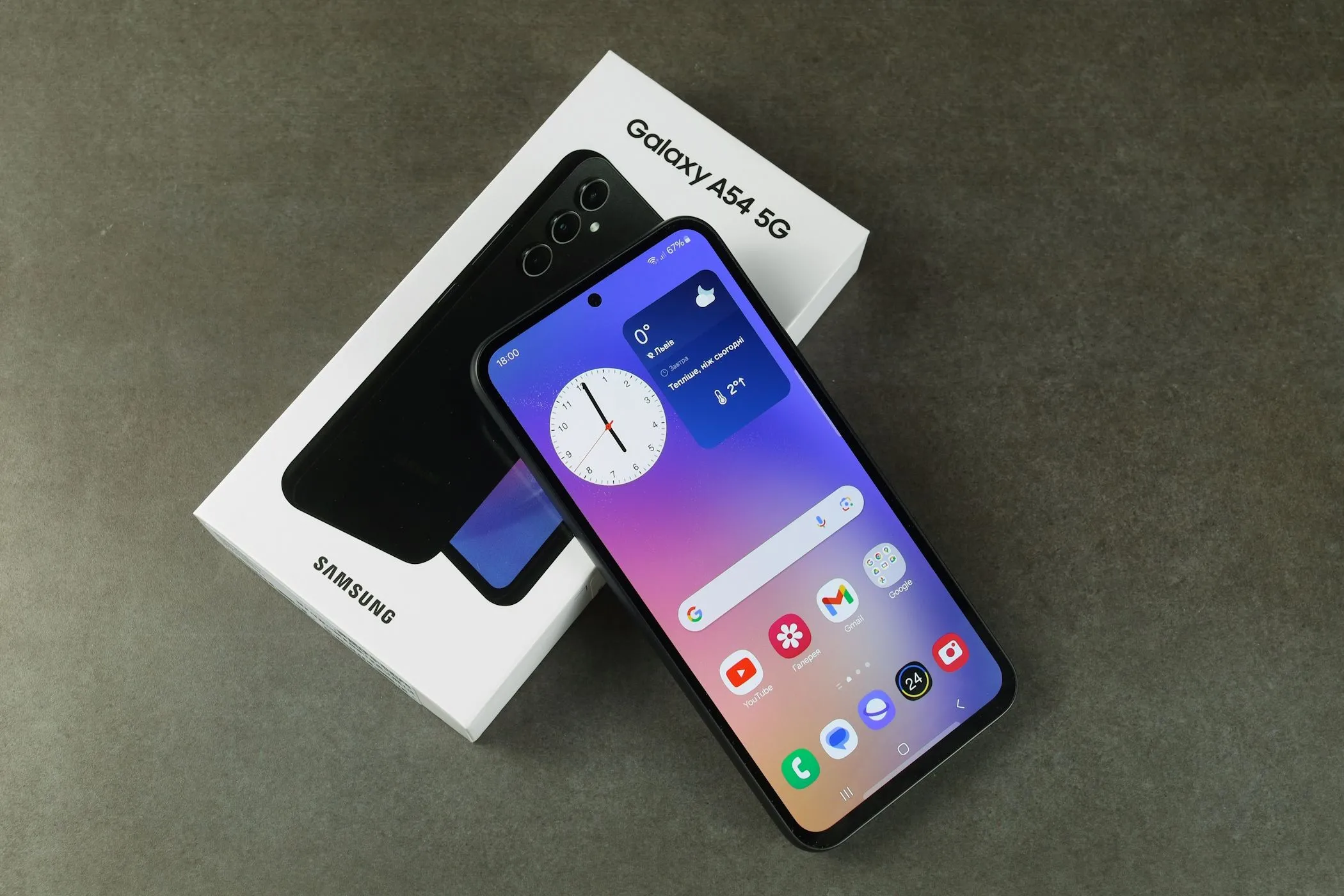 Chiếc điện thoại Samsung Galaxy A54 5G đặt cạnh hộp đựng sản phẩm, tượng trưng cho chu kỳ mua và nâng cấp thiết bị điện thoại.