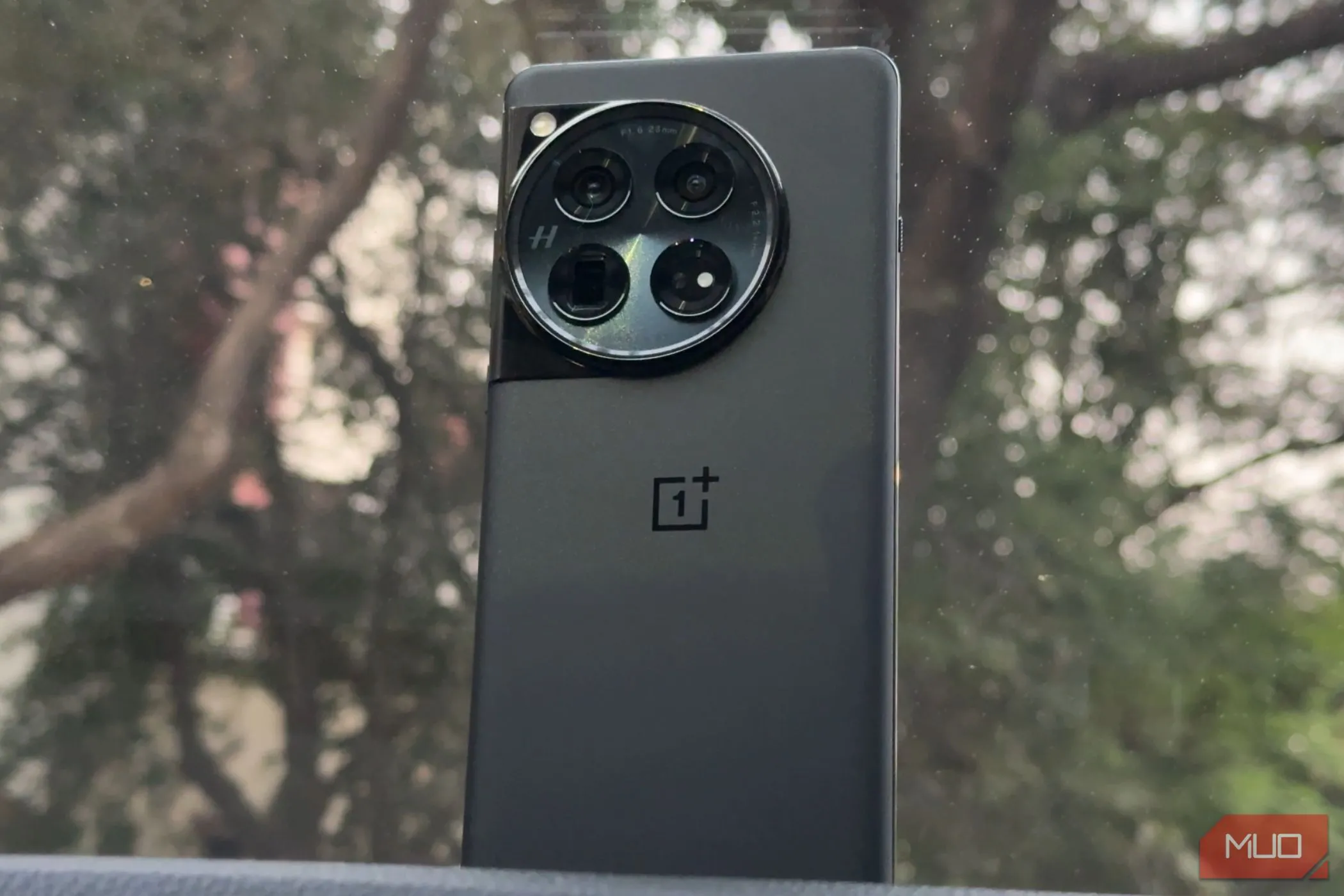 Điện thoại OnePlus 12 màu đen đặt trên bảng điều khiển xe ô tô, thể hiện sự sang trọng và tiện dụng