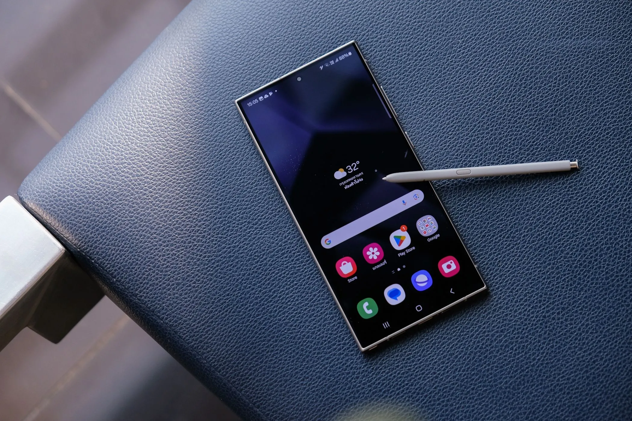 Điện thoại Samsung Galaxy S24 Ultra màu xám titan cùng bút S Pen đặt trên ghế