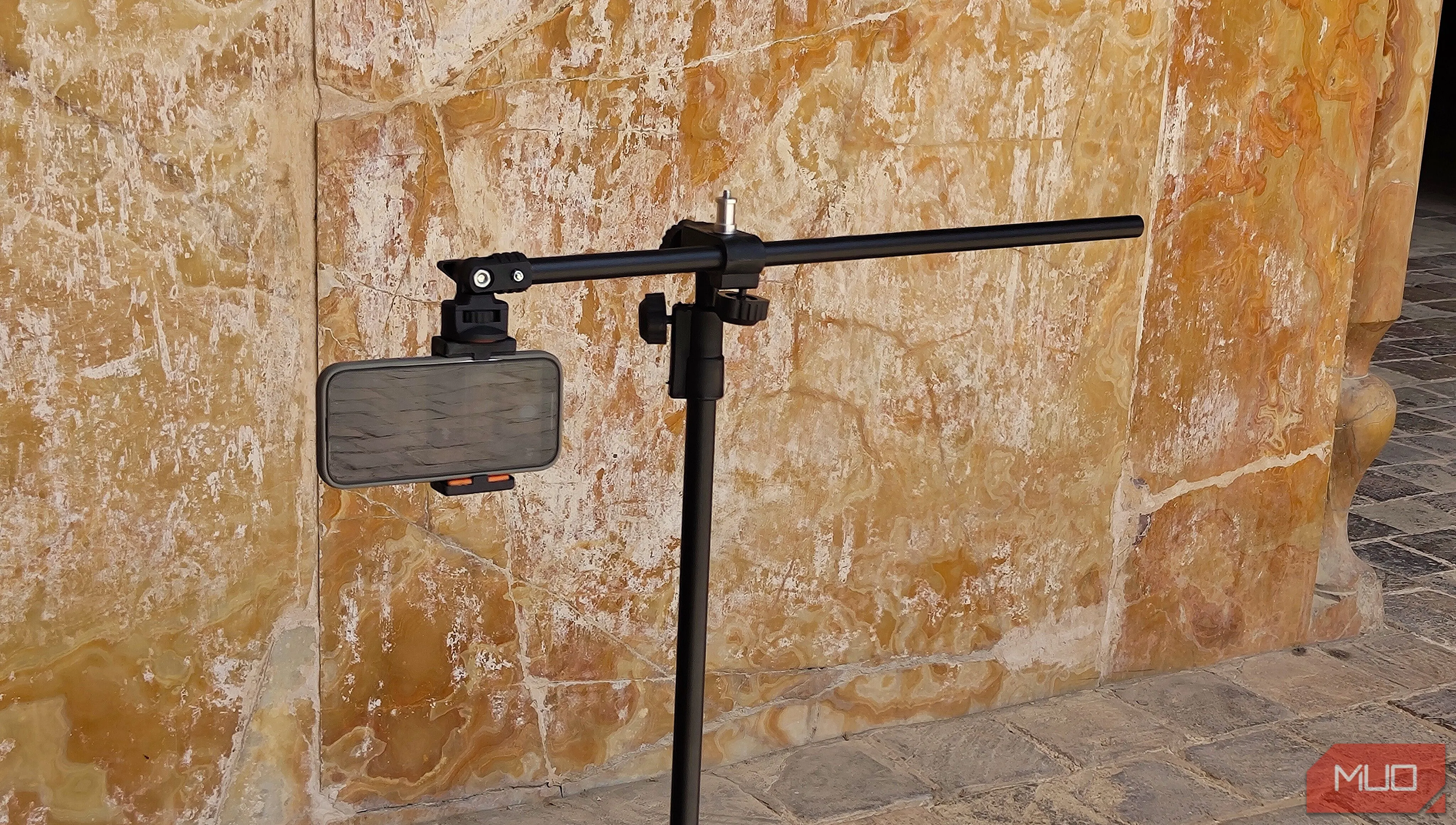 Điện thoại trên tripod hướng về phía bức tường cao, minh họa cách chọn chủ thể phù hợp cho panorama dọc
