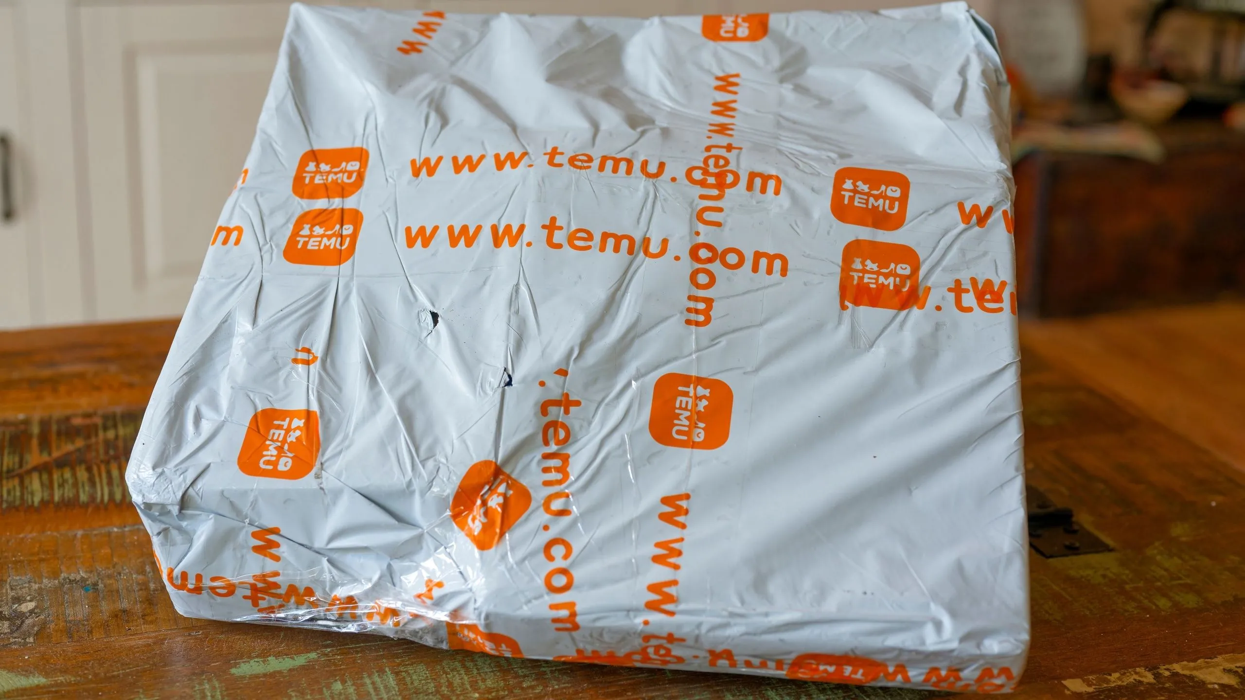 Gói hàng Temu được đặt trên bàn, minh họa cho việc mua sắm trực tuyến bị ảnh hưởng bởi chính sách thuế quan mới.