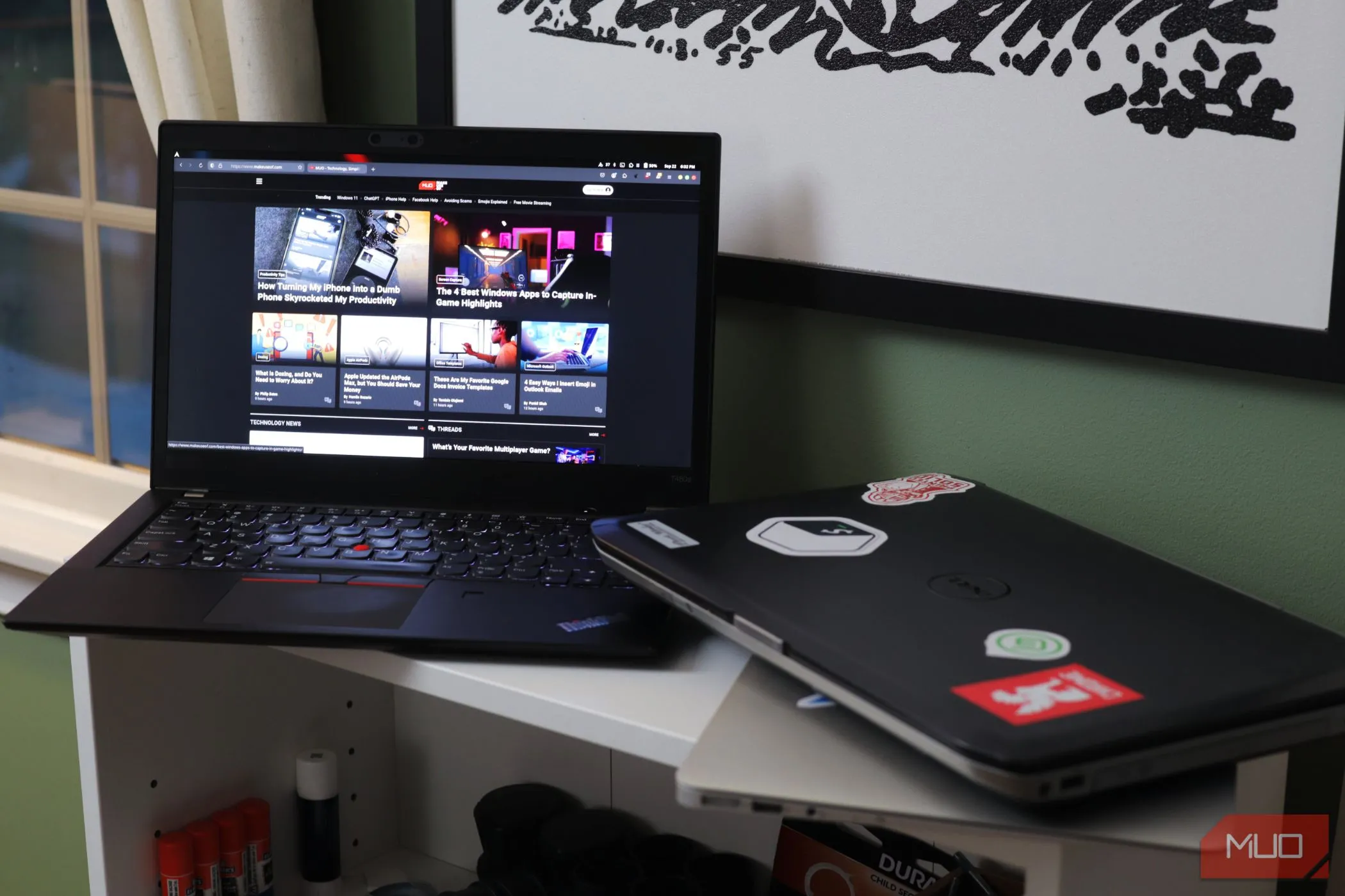 Hai chiếc laptop được đặt trên kệ màu trắng, tượng trưng cho việc sử dụng thiết bị chung có thể làm giảm bảo mật.