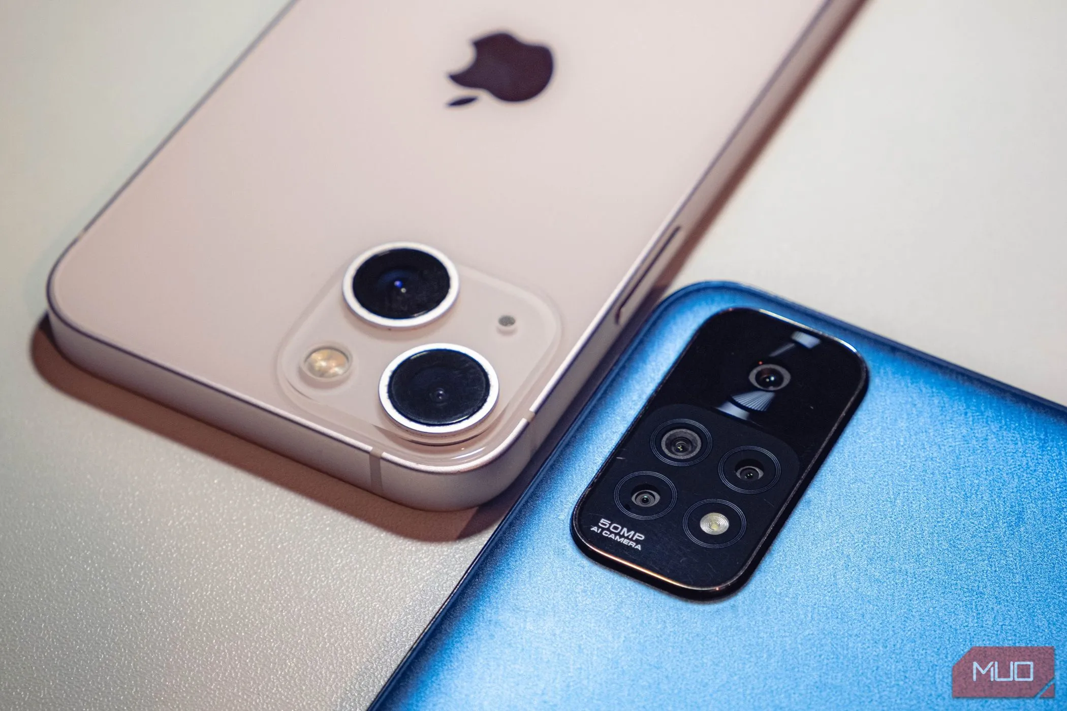 Hai chiếc smartphone màu xanh và hồng đặt úp trên bề mặt