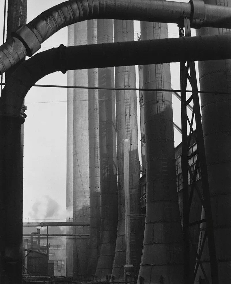 Hình ảnh đen trắng của Edward Weston miêu tả cảnh công nghiệp với các ống khói và cấu trúc kim loại đồ sộ, nhấn mạnh tính trừu tượng của hình khối
