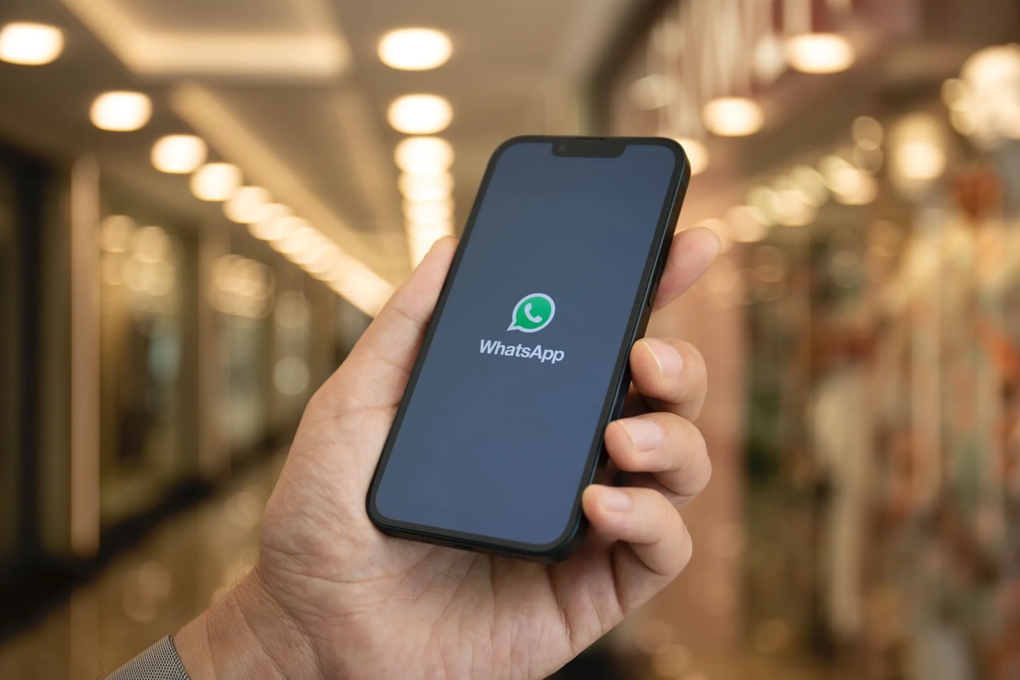 Hình ảnh người dùng cầm điện thoại thông minh hiển thị biểu tượng ứng dụng WhatsApp, minh họa tính năng phiên âm tin nhắn thoại.