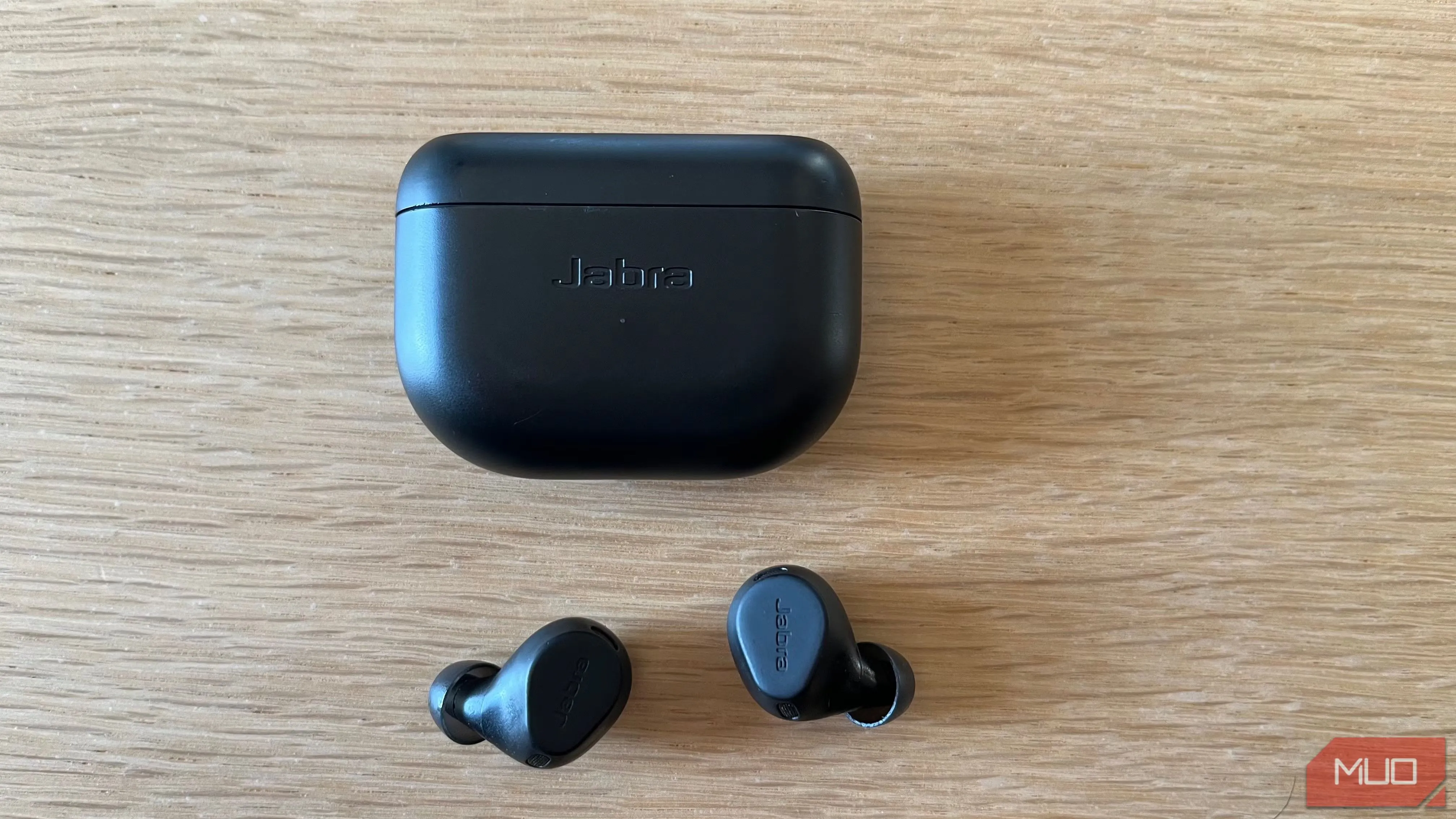 Hình ảnh tai nghe không dây Jabra Elite 8 Active màu đen đặt trên bàn gỗ, nổi bật tính năng chống ồn và thiết kế thể thao