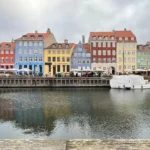 Kênh đào Nyhavn với những ngôi nhà nhiều màu sắc và hình ảnh phản chiếu trên mặt nước, chụp từ góc thấp.