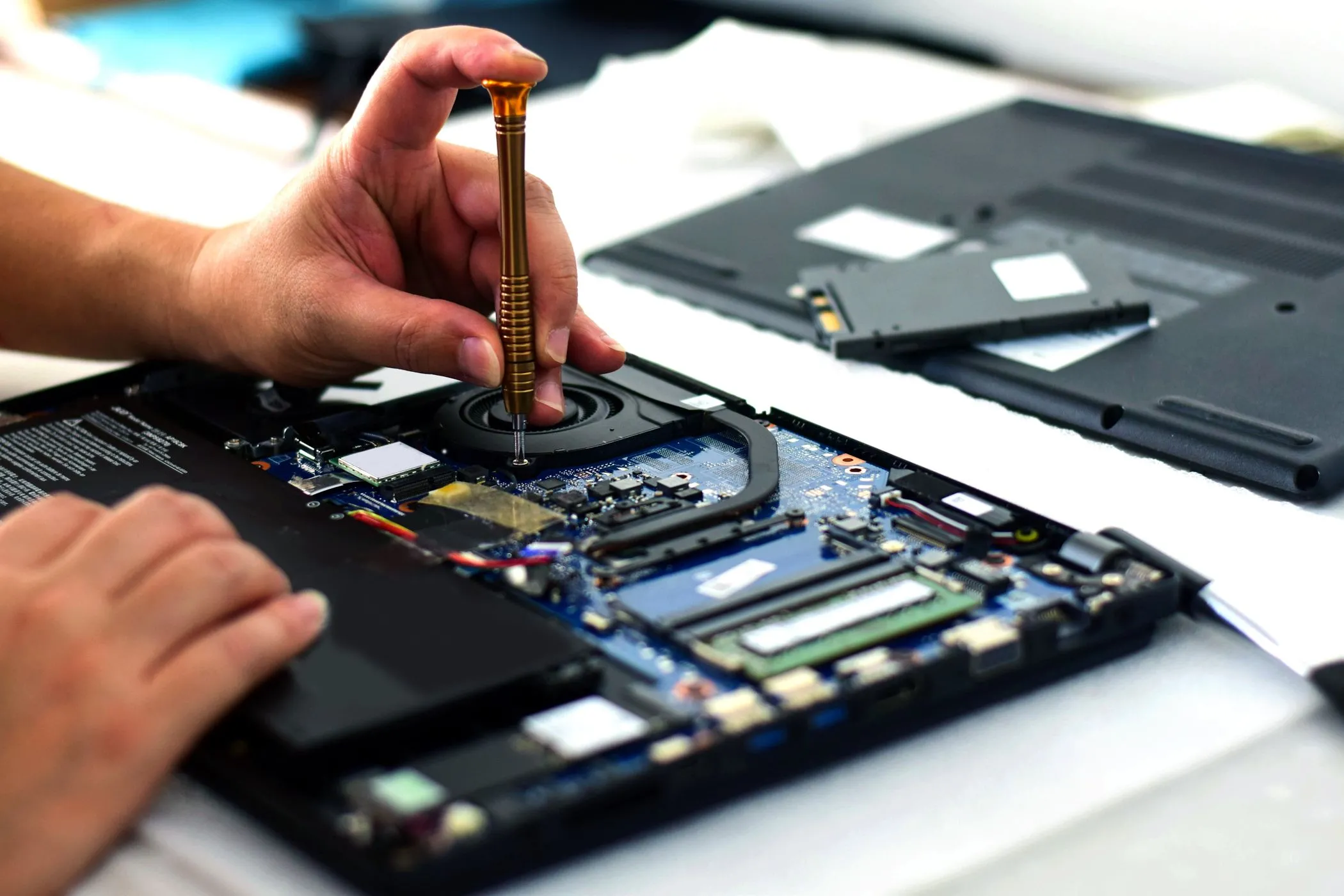Kỹ thuật viên đang dùng tua vít sửa chữa mainboard laptop với các linh kiện nhỏ