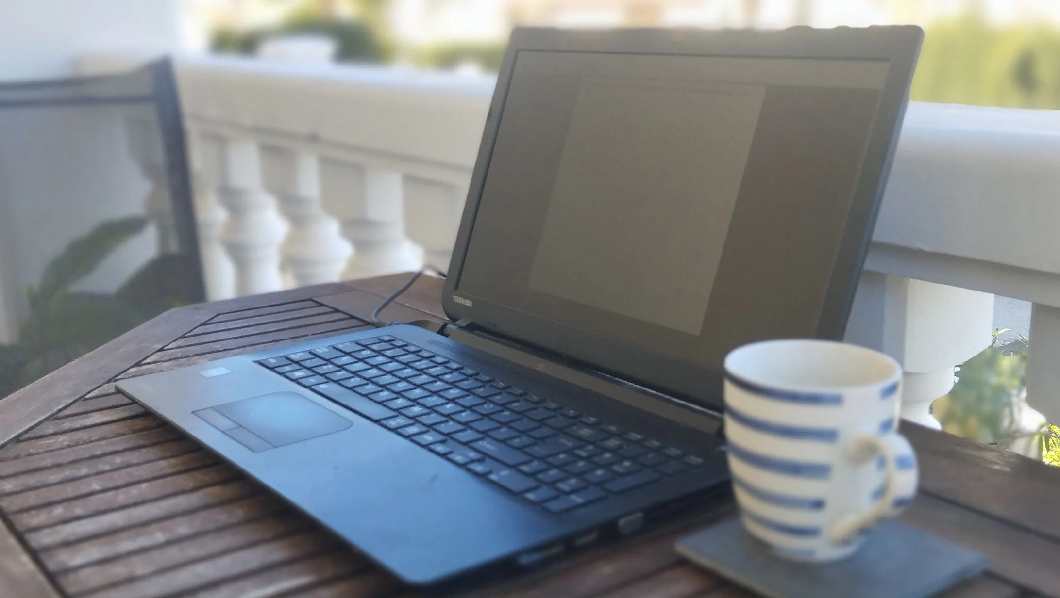 Laptop Toshiba trên bàn cùng cốc cà phê