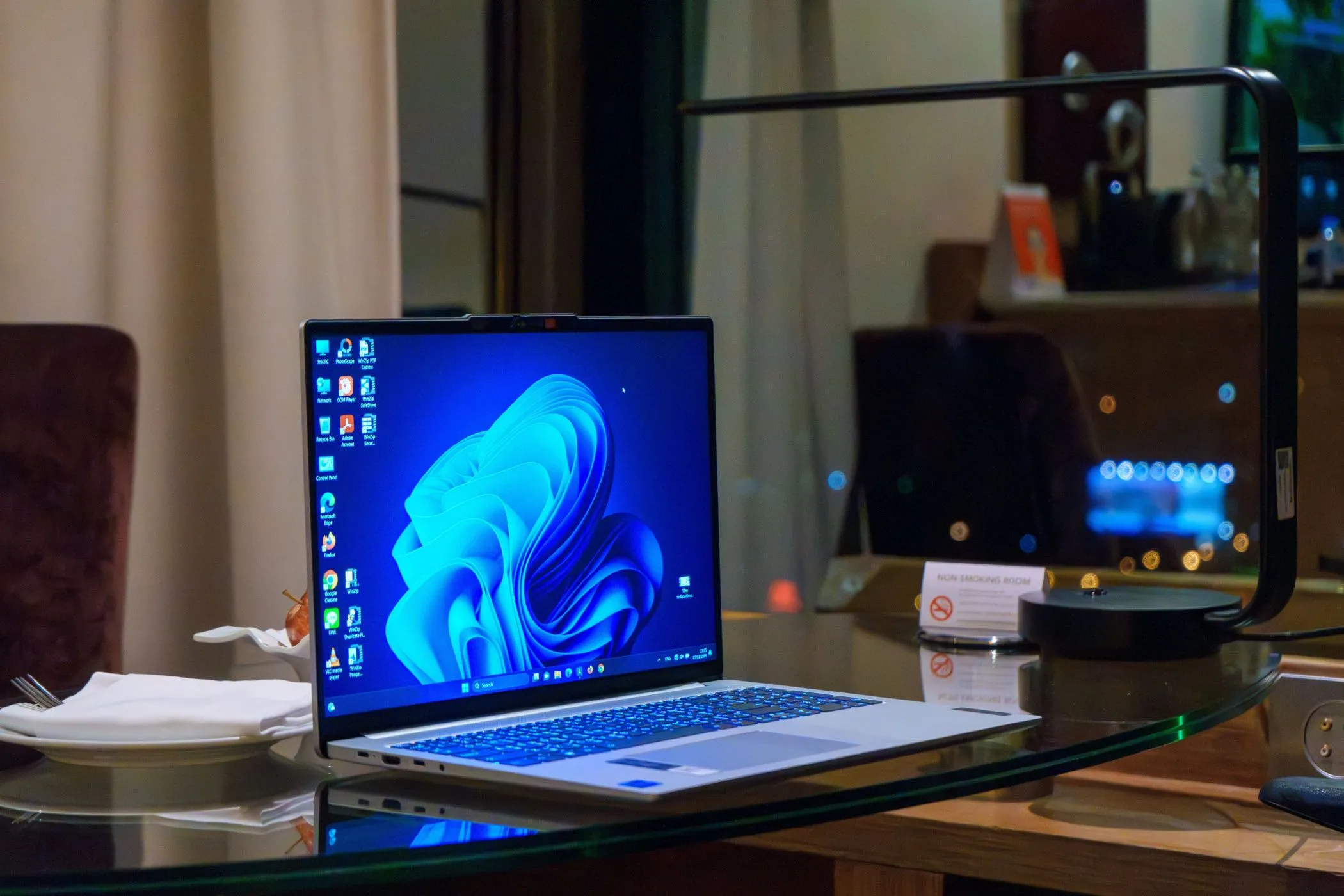 Laptop Windows trên bàn kính với các biểu tượng desktop