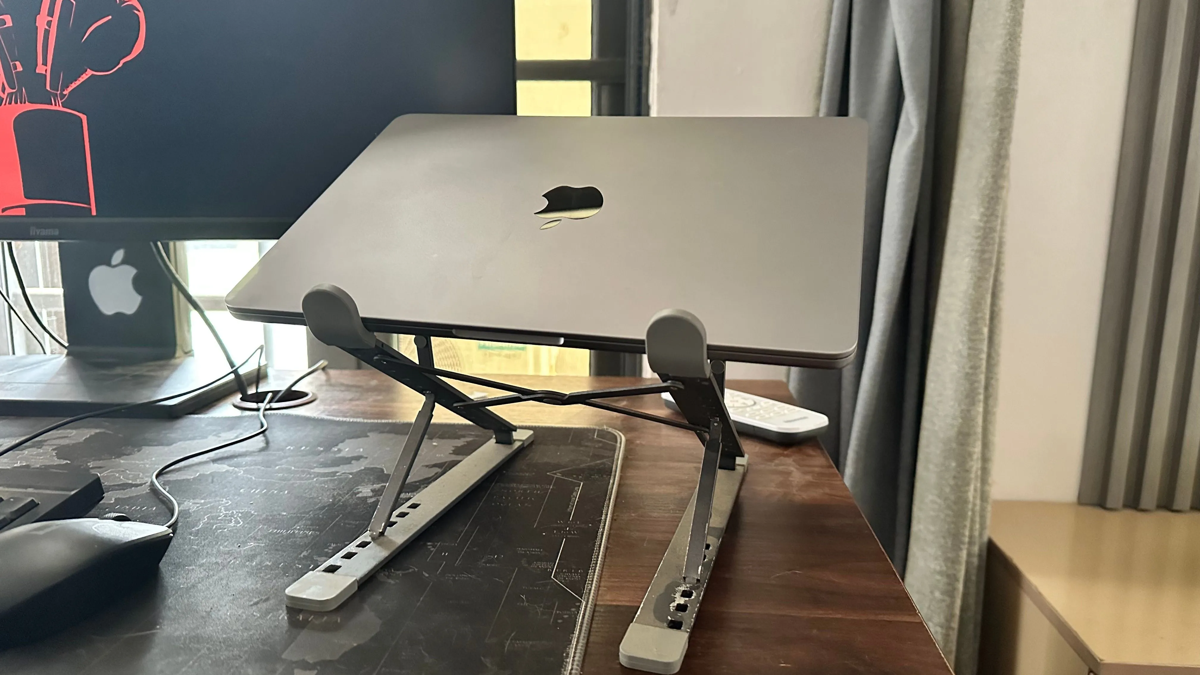 MacBook đặt trên giá đỡ laptop cạnh màn hình ngoài, cho thấy cách bố trí tối ưu cho không gian làm việc.