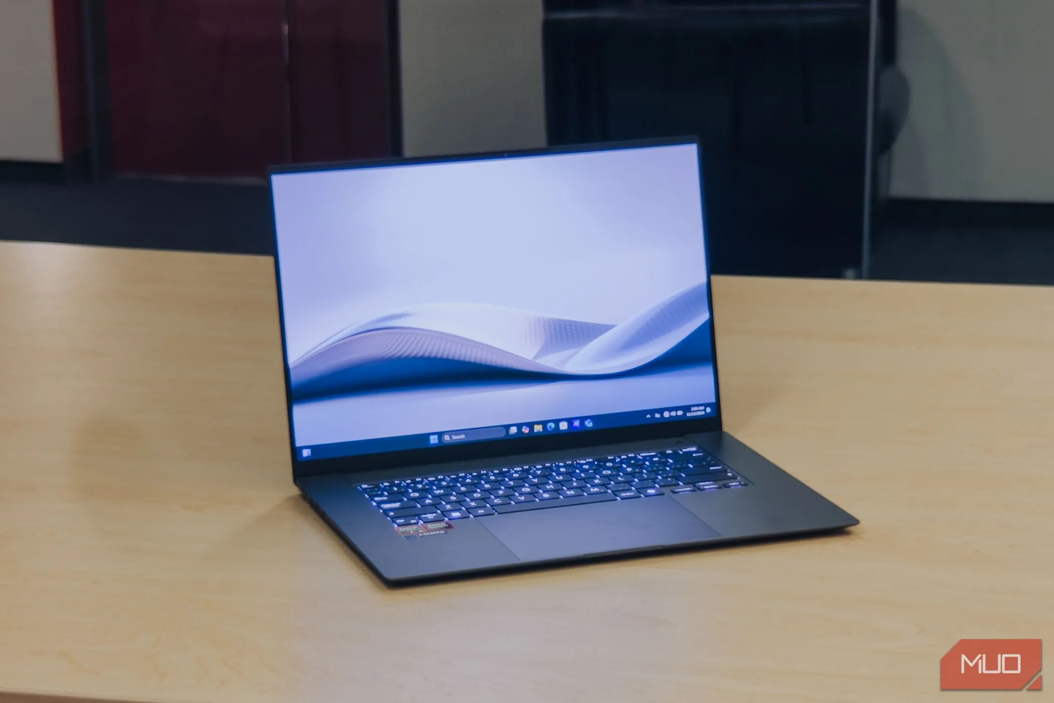 Màn hình ASUS Zenbook S 16 OLED bật ở góc trên bàn gỗ