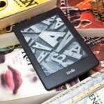 Máy đọc sách Kindle đặt trên chồng sách giấy, thể hiện sự khác biệt về quyền sở hữu nội dung số