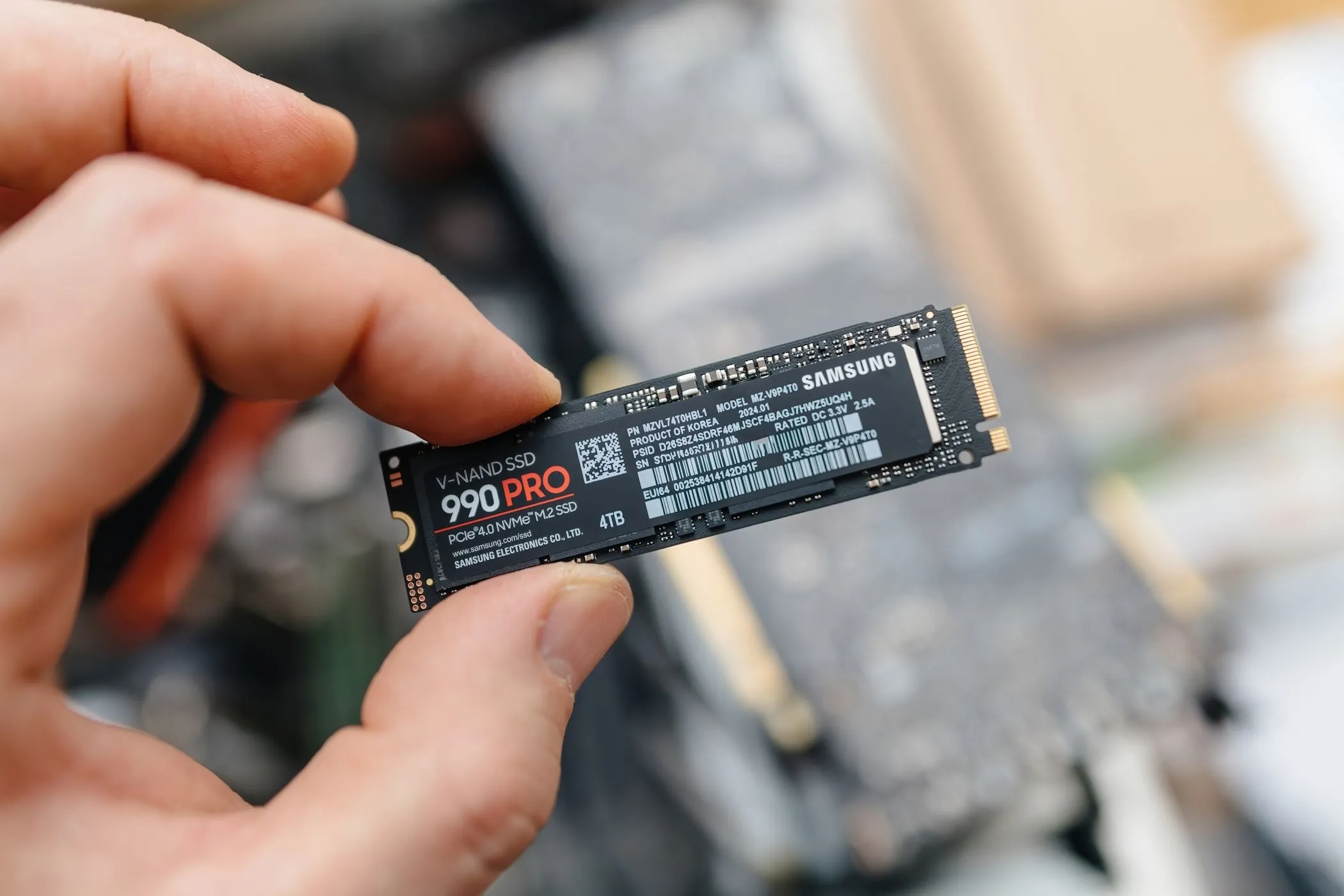 Một người đàn ông đang cầm trên tay ổ cứng SSD Samsung 990 Pro NVMe, đại diện cho dòng sản phẩm SSD hiệu năng cao.