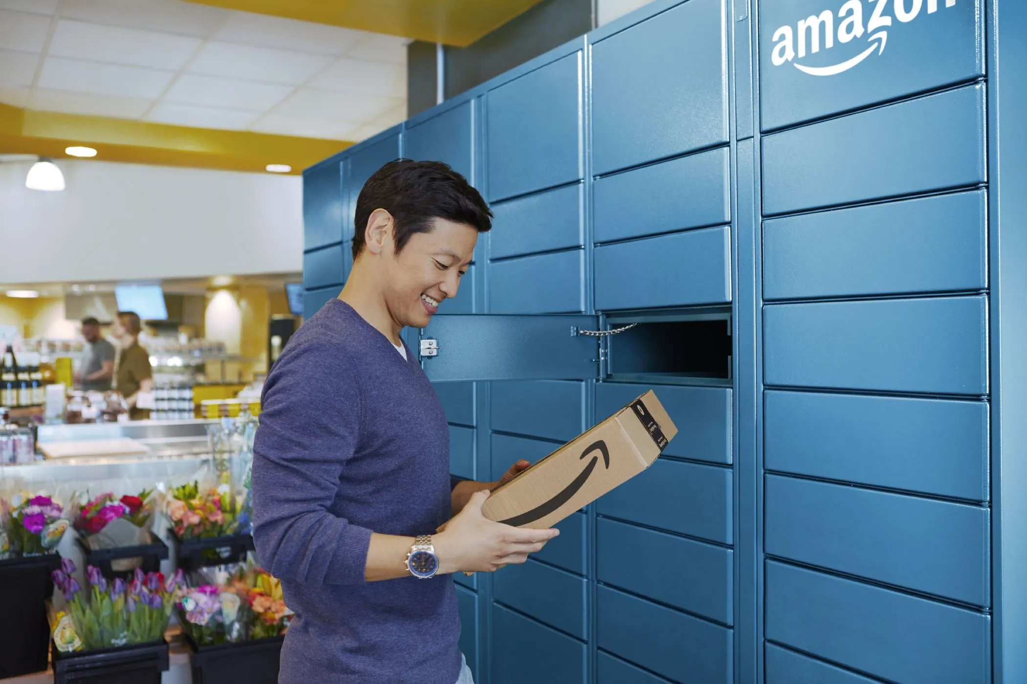 Một người đàn ông đang nhận gói hàng từ tủ khóa Amazon Locker, minh họa phương pháp nhận hàng ẩn danh để bảo vệ địa chỉ nhà riêng khi mua sắm trực tuyến