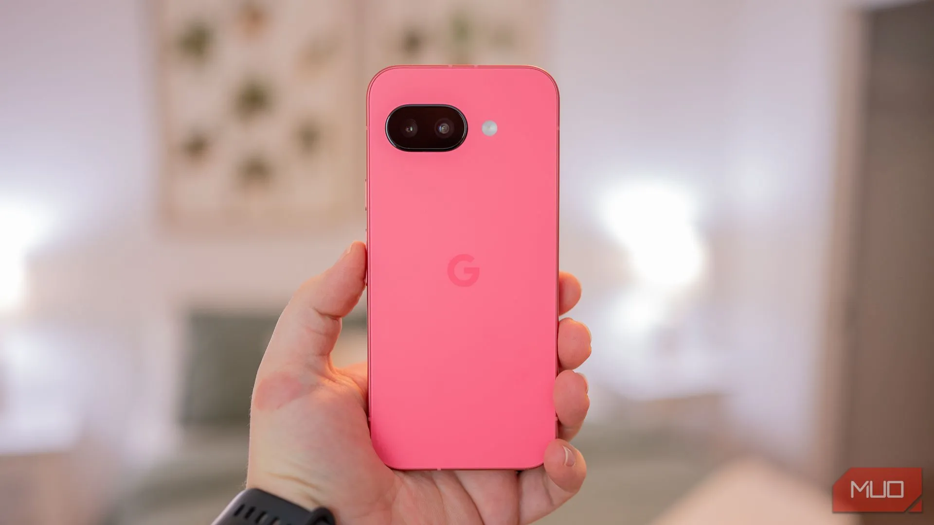 Một người đang cầm Google Pixel 9a cho thấy mặt lưng của điện thoại với thiết kế tối giản màu tím Iris