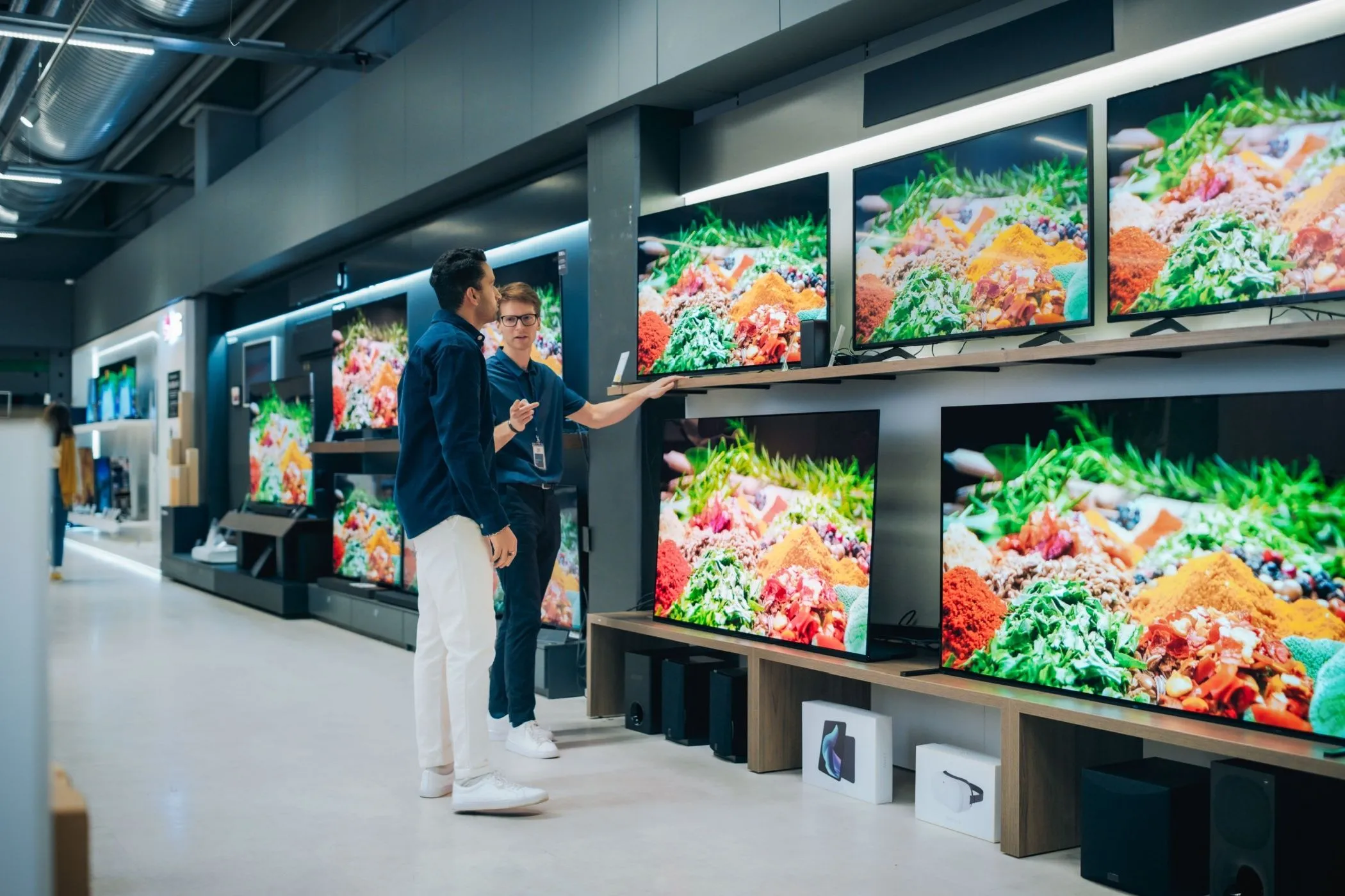 Một nhân viên cửa hàng đang giới thiệu TV cho khách hàng.