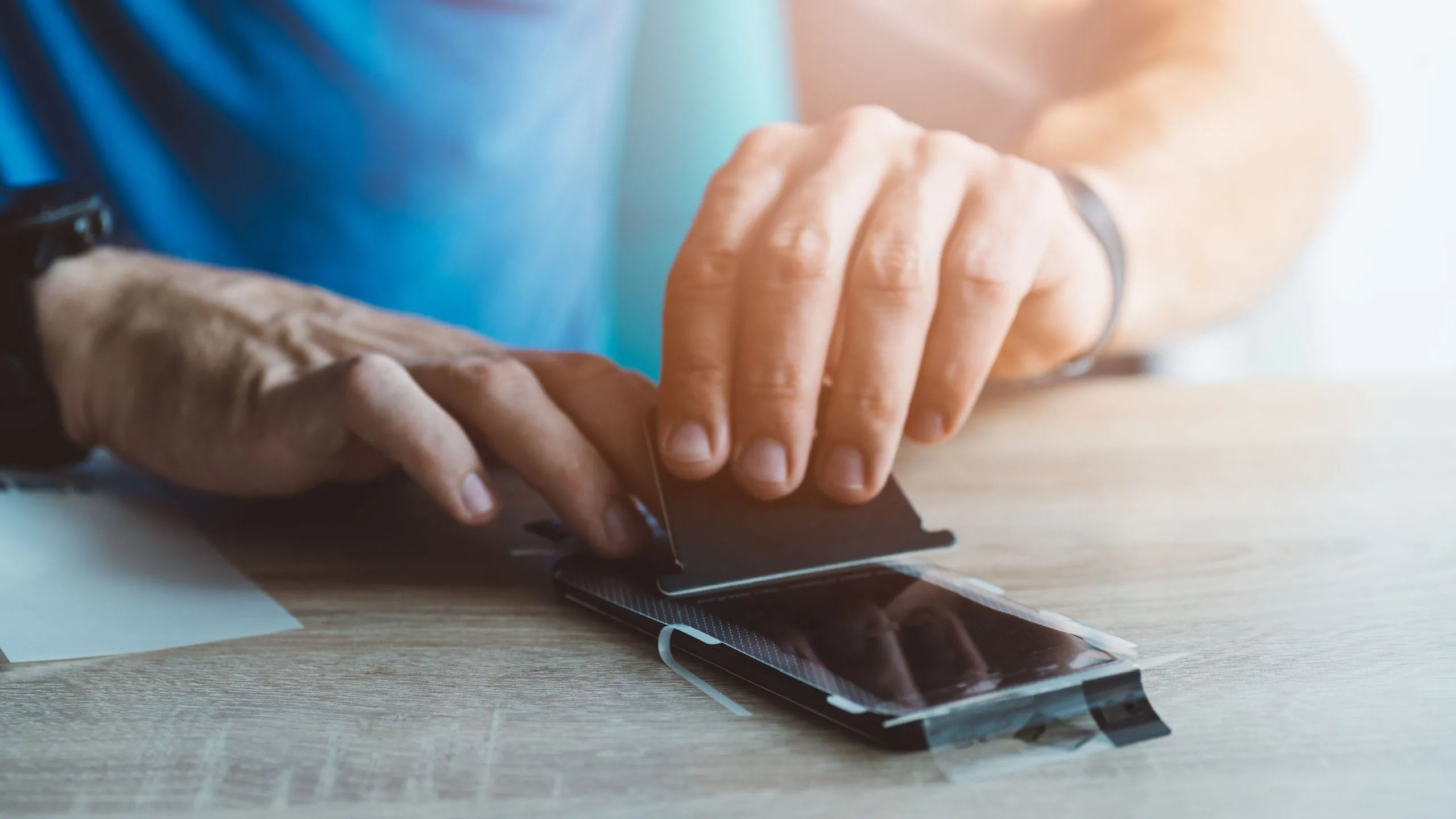 Người đàn ông dán miếng bảo vệ màn hình lên điện thoại iPhone