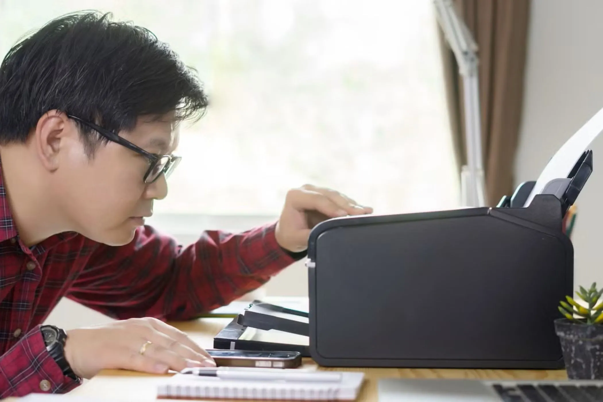 Người đàn ông đang kiểm tra máy in trên bàn làm việc
