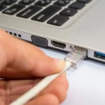 Người đàn ông kết nối cáp mạng Ethernet vào laptop Windows để tăng bảo mật và tốc độ internet