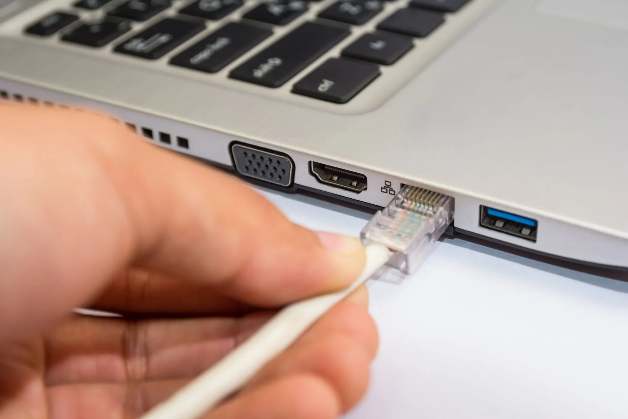 Người đàn ông kết nối cáp mạng Ethernet vào laptop Windows để tăng bảo mật và tốc độ internet