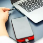 Người dùng đang cắm cáp USB-C từ pin dự phòng vào laptop khi sạc