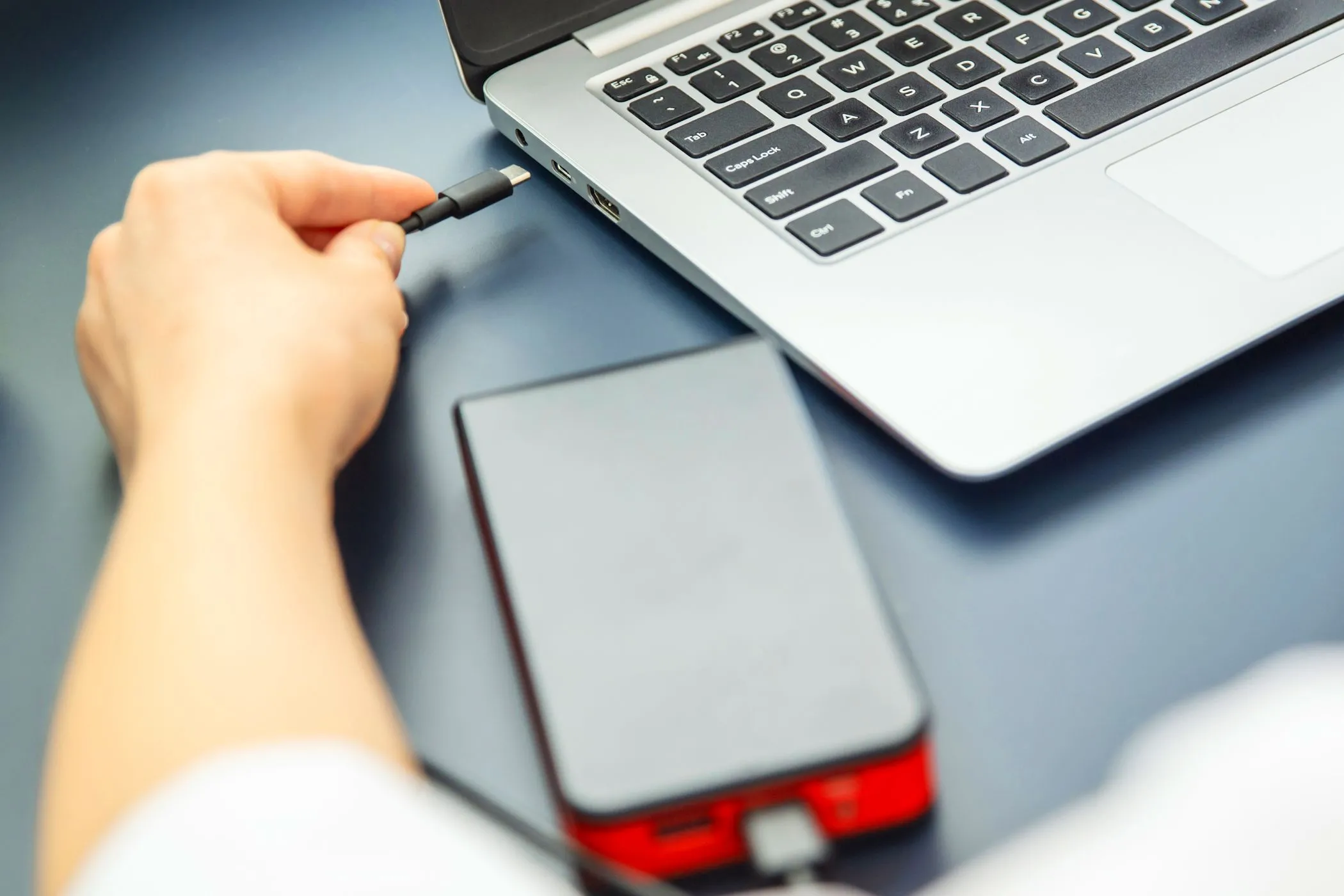 Người dùng đang cắm cáp USB-C từ pin dự phòng vào laptop khi sạc