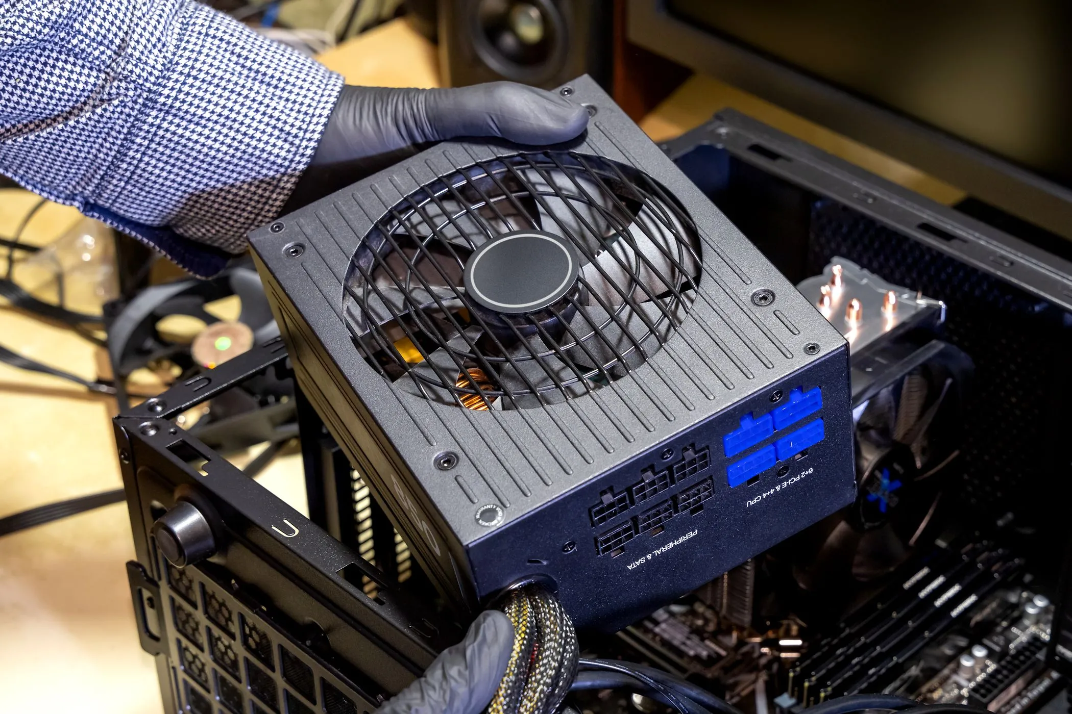 Người dùng đang lắp đặt bộ nguồn (PSU) vào khoang vỏ máy tính để bàn, nhấn mạnh tầm quan trọng của nguồn điện ổn định cho SSD