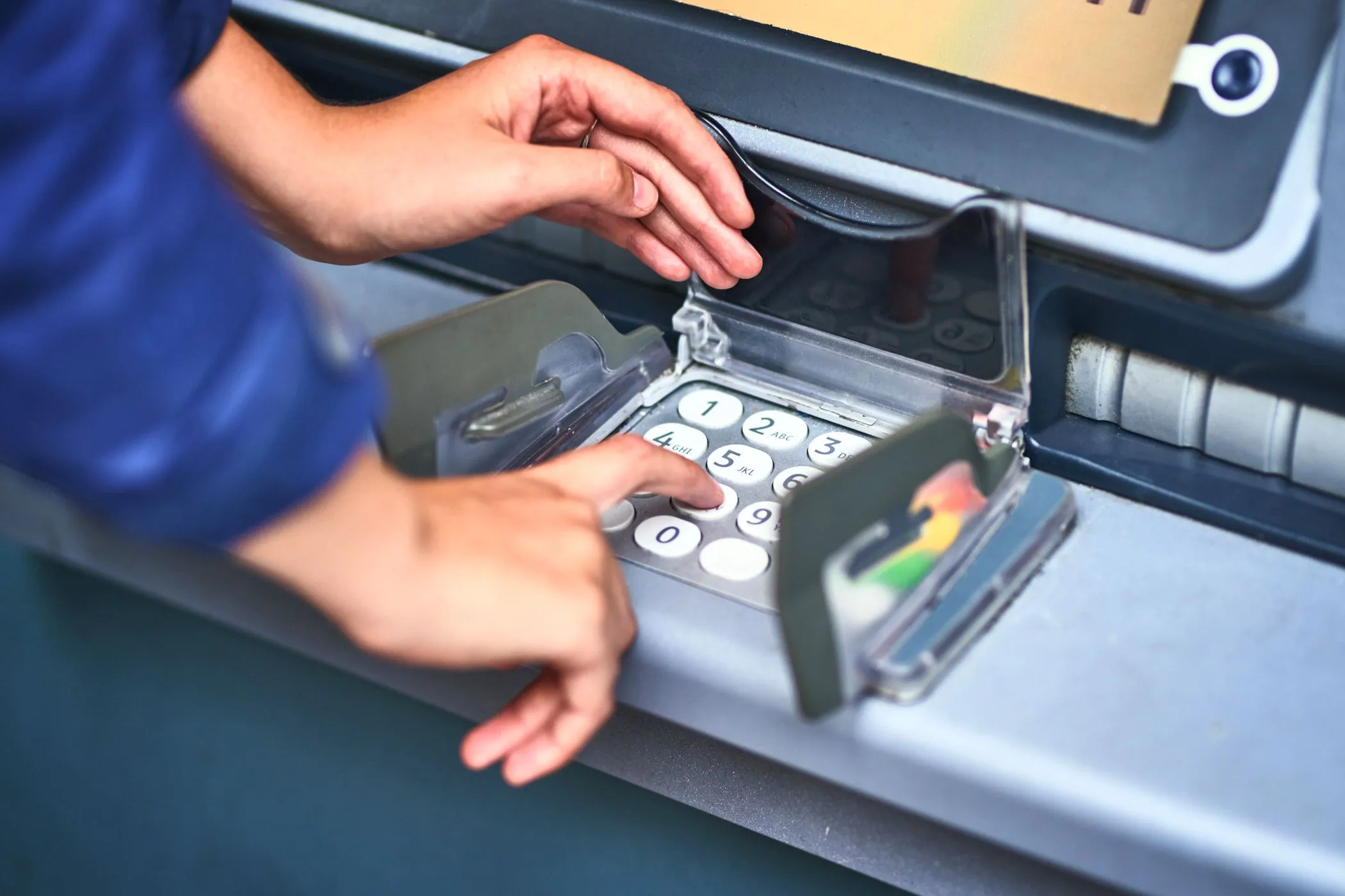 Người dùng đang nhập mã PIN trên bàn phím của máy ATM, minh họa nguy cơ lộ thông tin cá nhân.