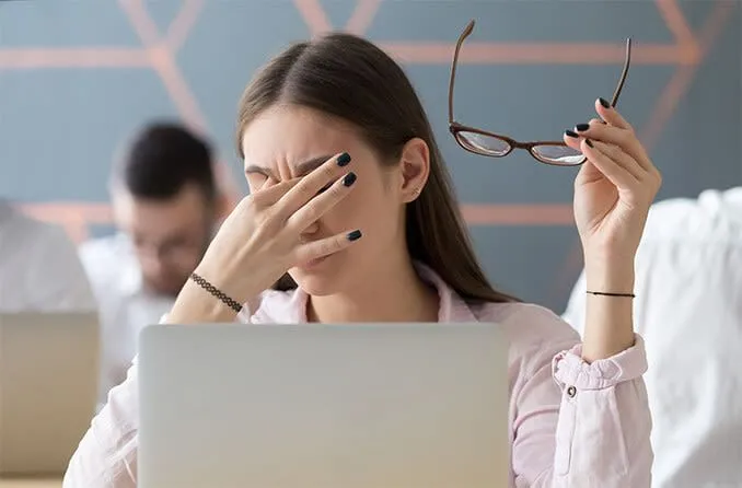 Người phụ nữ dụi mắt do căng thẳng thị giác kỹ thuật số vì dùng màn hình