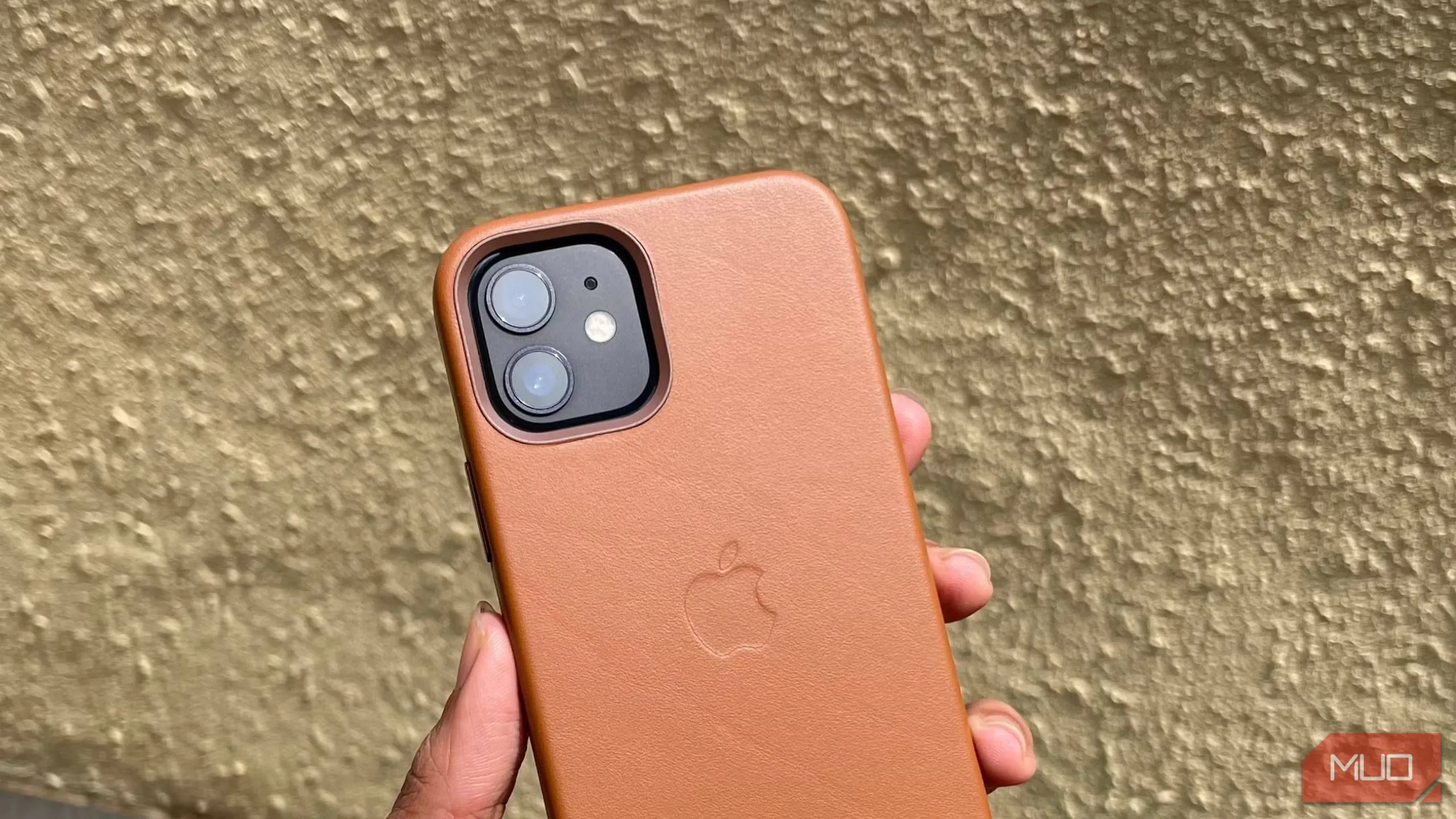 Ốp lưng da màu nâu cho iPhone 12 đang được cầm trên tay, thể hiện vẻ ngoài cao cấp và bền bỉ của phụ kiện Apple trước đây.
