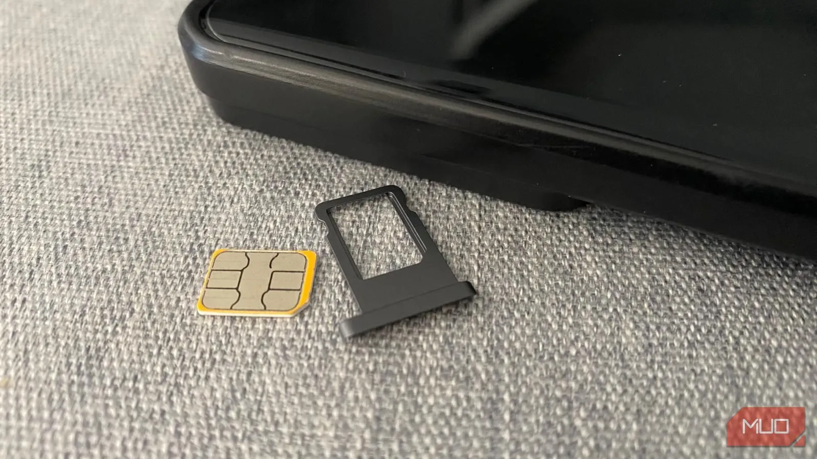 Thẻ SIM và khay đựng đặt cạnh điện thoại di động trên bàn