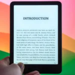 Thiết bị đọc sách điện tử Amazon Kindle Paperwhite Signature Edition đặt trước màn hình máy tính, minh họa cho tính năng tóm tắt sách Recaps.