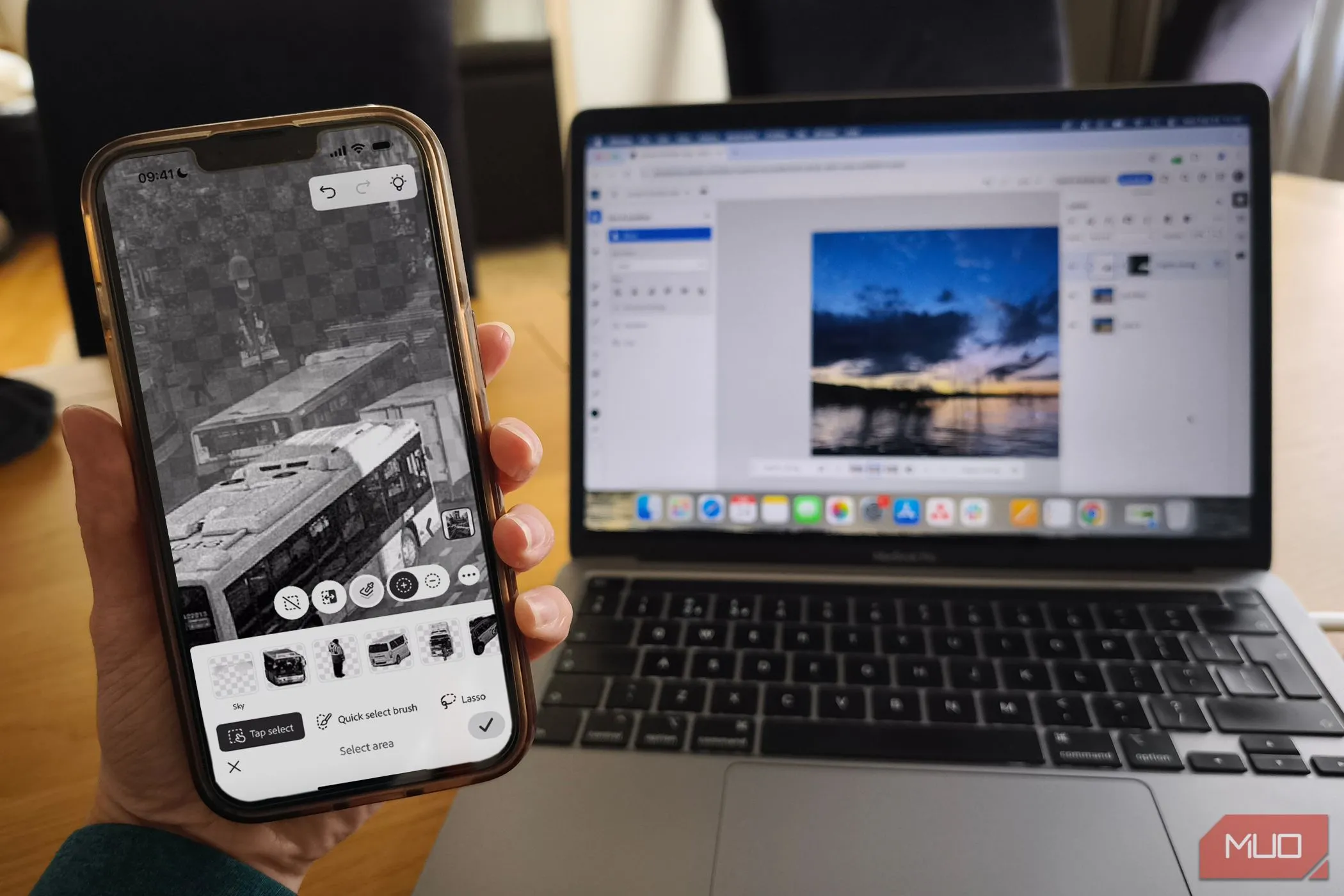 Ứng dụng Photoshop Mobile và phiên bản nền web được hiển thị trên MacBook, minh họa khả năng đồng bộ đa nền tảng.