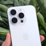 iPhone 16 Pro màu trắng trong tay trước cây xanh