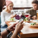 Khách du lịch đang dùng điện thoại kiểm tra Wi-Fi trong quán cà phê