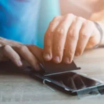 Người đàn ông dán miếng bảo vệ màn hình lên điện thoại iPhone