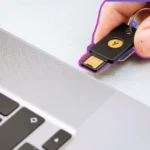 Người dùng cắm USB Yubico vào cổng USB laptop để khóa máy tính, minh họa việc sử dụng USB như một chìa khóa bảo mật vật lý.
