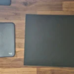 Thảm lót chuột Logitech và miếng lót chuột kính cường lực so sánh bên cạnh nhau, thể hiện sự khác biệt về chất liệu và thiết kế.